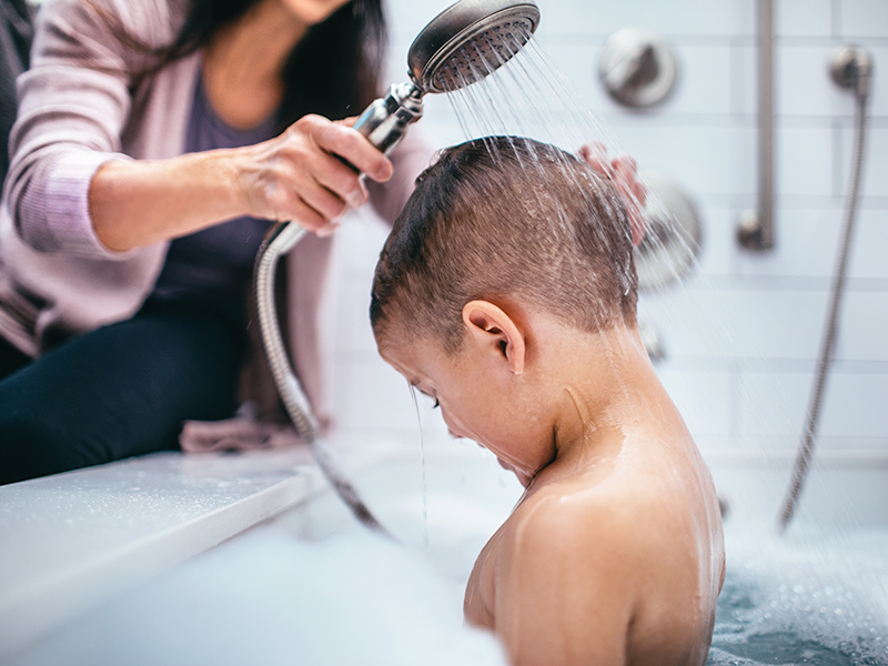 Mother washing son's hair in bathtub